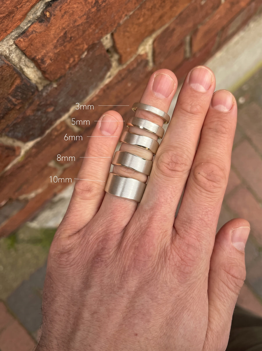 Silver wedding rings with a brushed finish and hammered sides, shown in widths ranging from 3mm to 10mm.