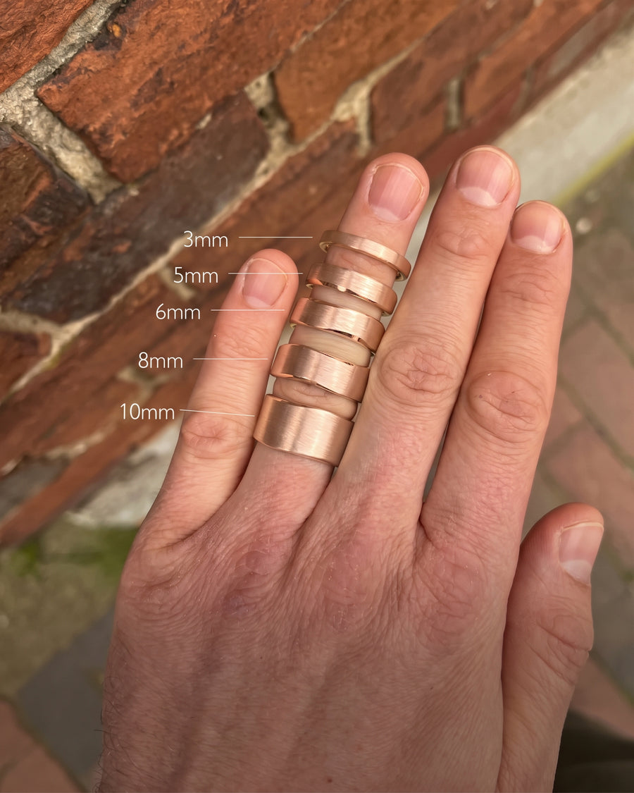 Rose gold wedding rings with a brushed finish and hammered sides, shown in widths from 3mm to 10mm.