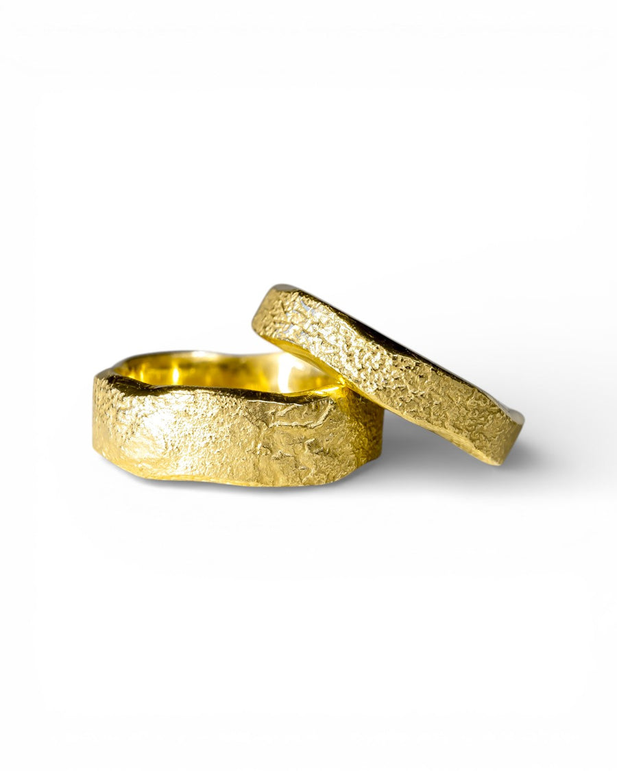 Pair of hammered gold rings with organic, textured finish on a white background