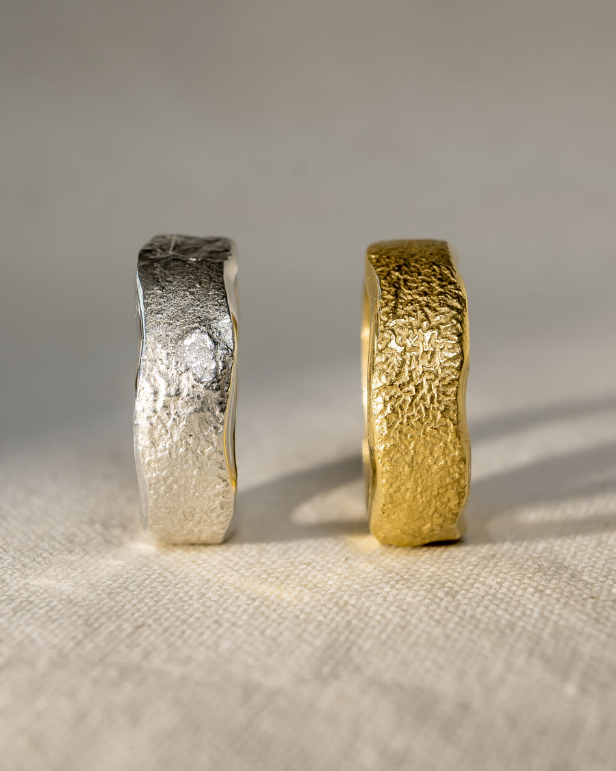 Textured gold and silver wedding rings with organic, handmade design on fabric