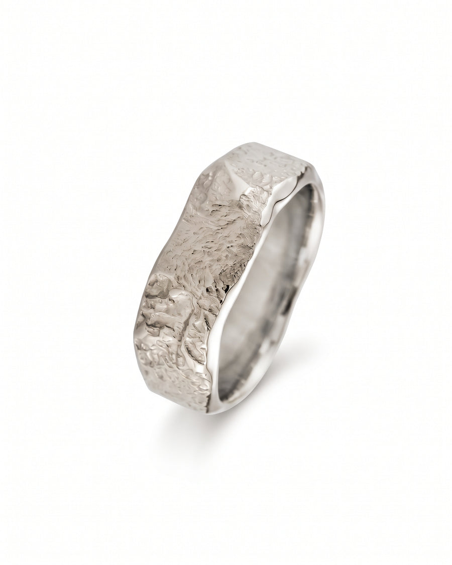 Silver wedding band with a textured, hammered finish and a wide, organic shape.