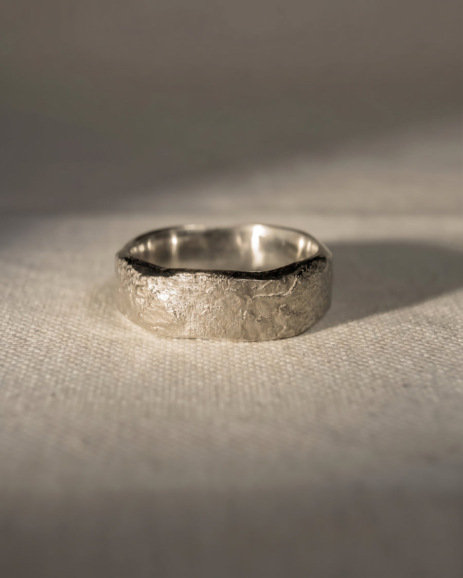 4mm platinum wedding band with a textured, hammered finish on a neutral fabric background.