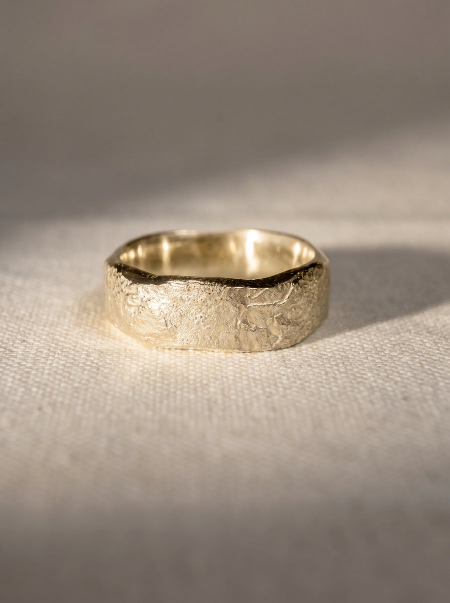 4mm 9ct white gold wedding band with a textured, hammered finish on a neutral fabric background.