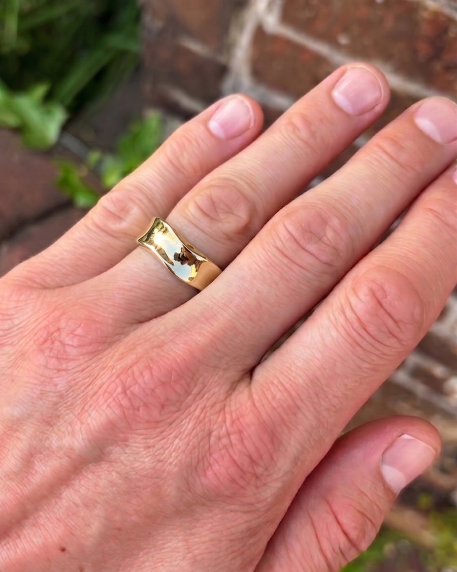 Men's gold side hammered wedding ring on a hand.