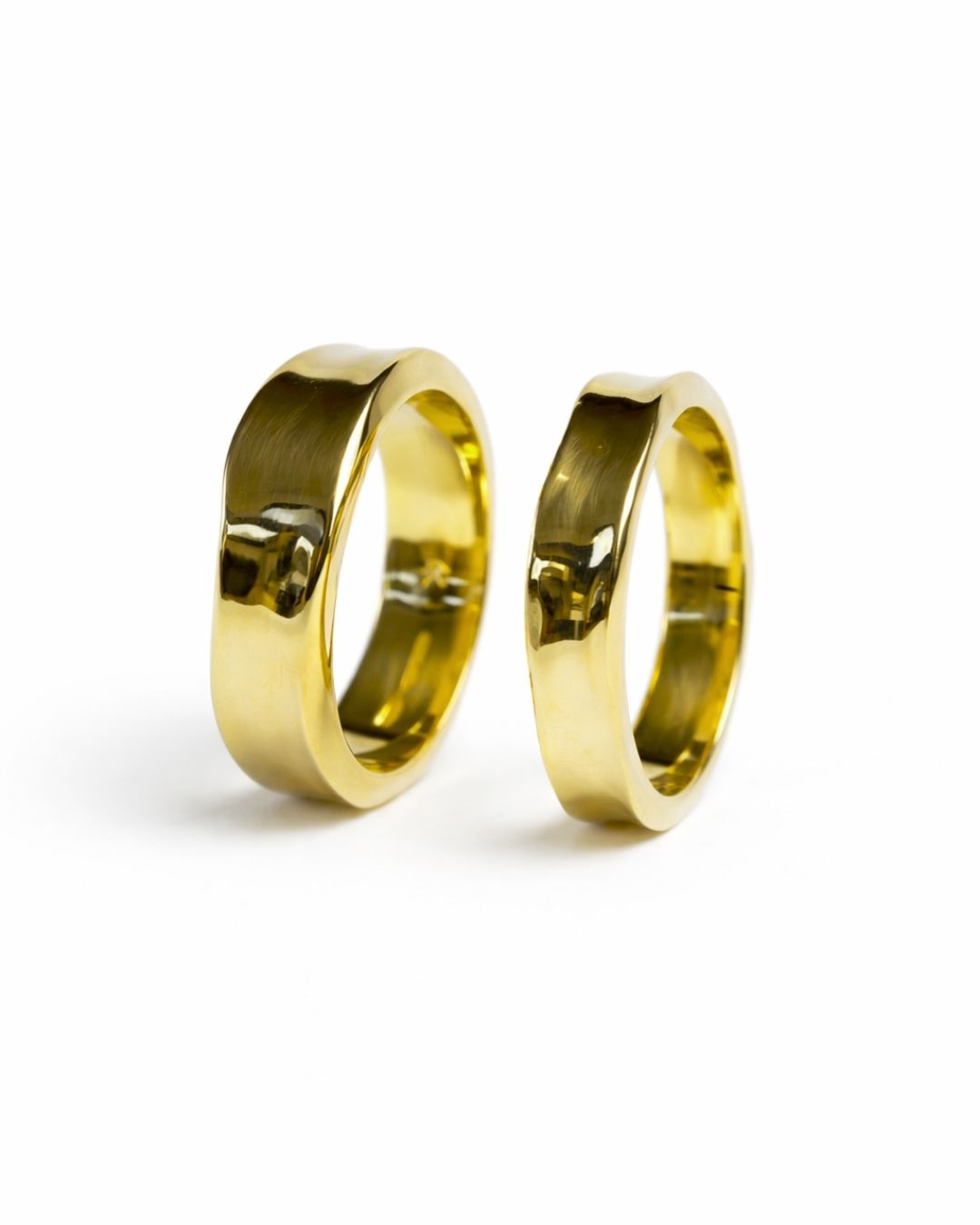 Two gold side hammered wedding rings, one wider than the other.