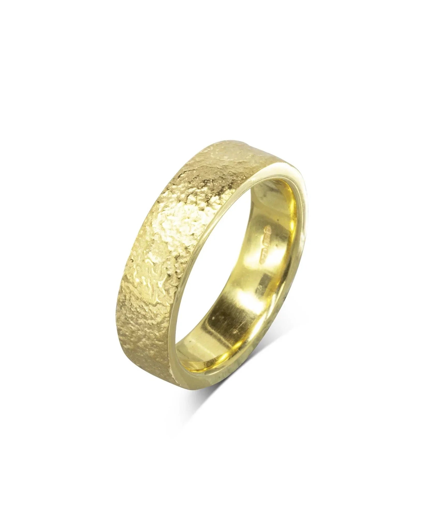 Textured yellow gold wedding ring with a hammered finish on a white background
