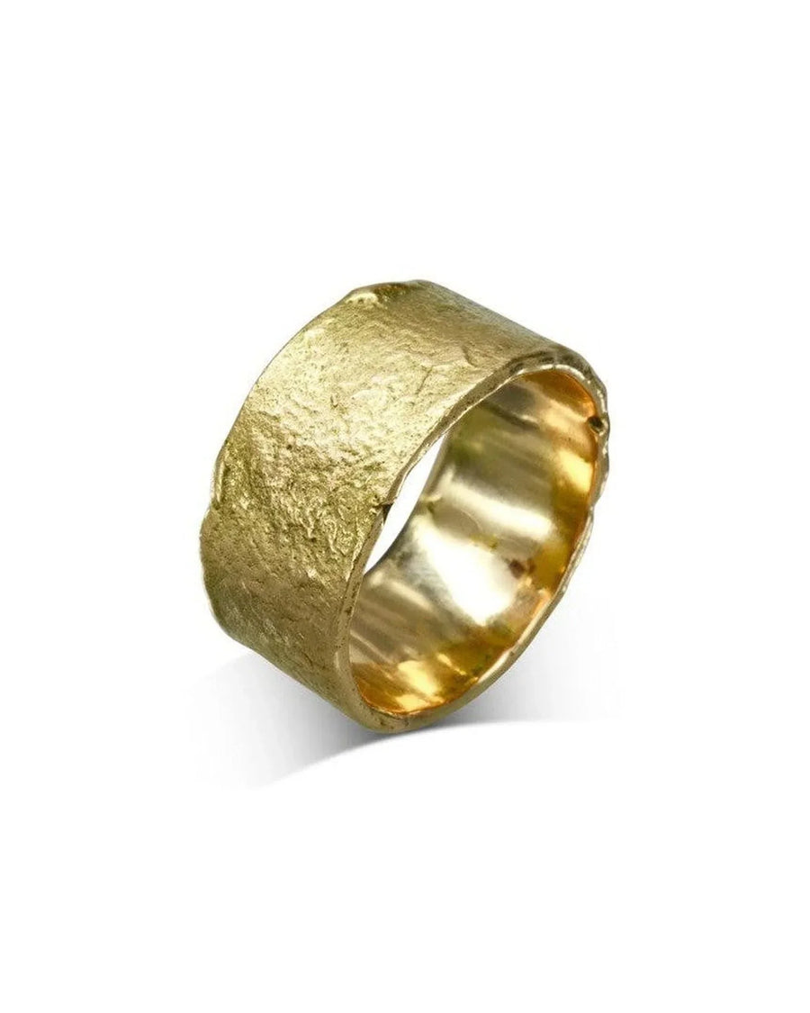 Wide gold wedding band with organic, textured finish on a white background