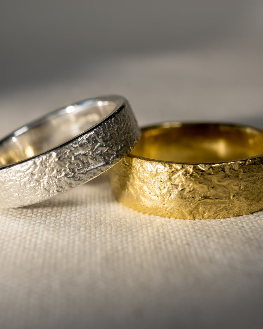 Textured gold and silver wedding rings on cream fabric