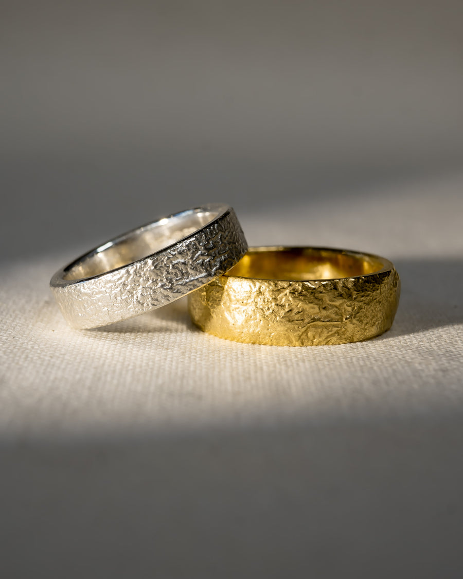 Textured silver and gold wedding rings with organic, handmade finish on fabric