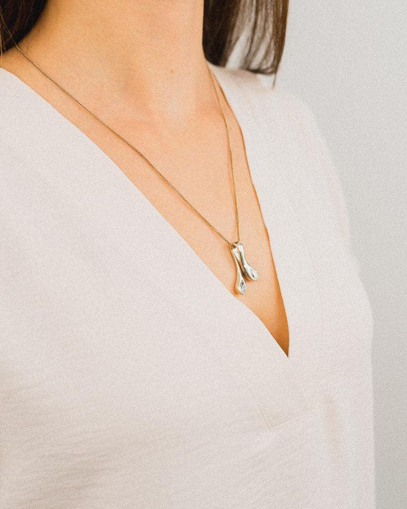 Gold organic drop pendant necklace with diamonds on woman wearing cream blouse