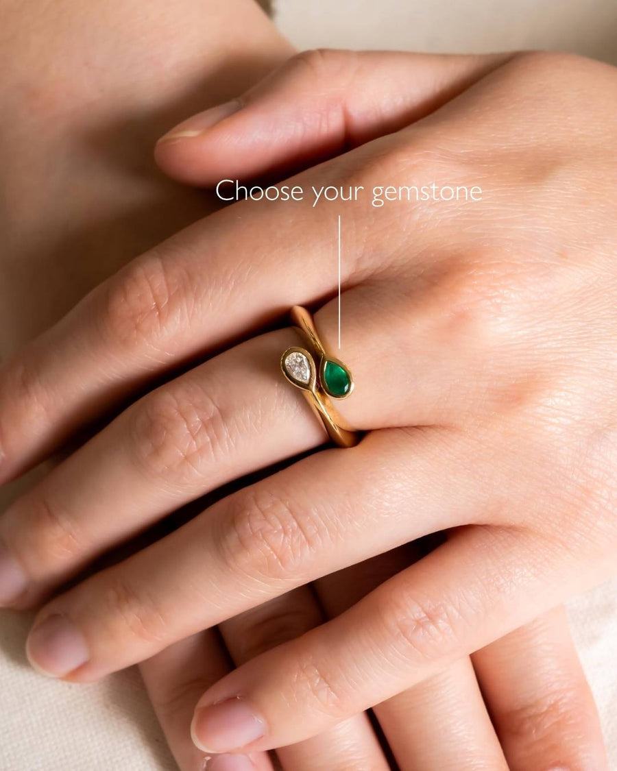 Gold ring with pear-shaped diamond and emerald gemstones.