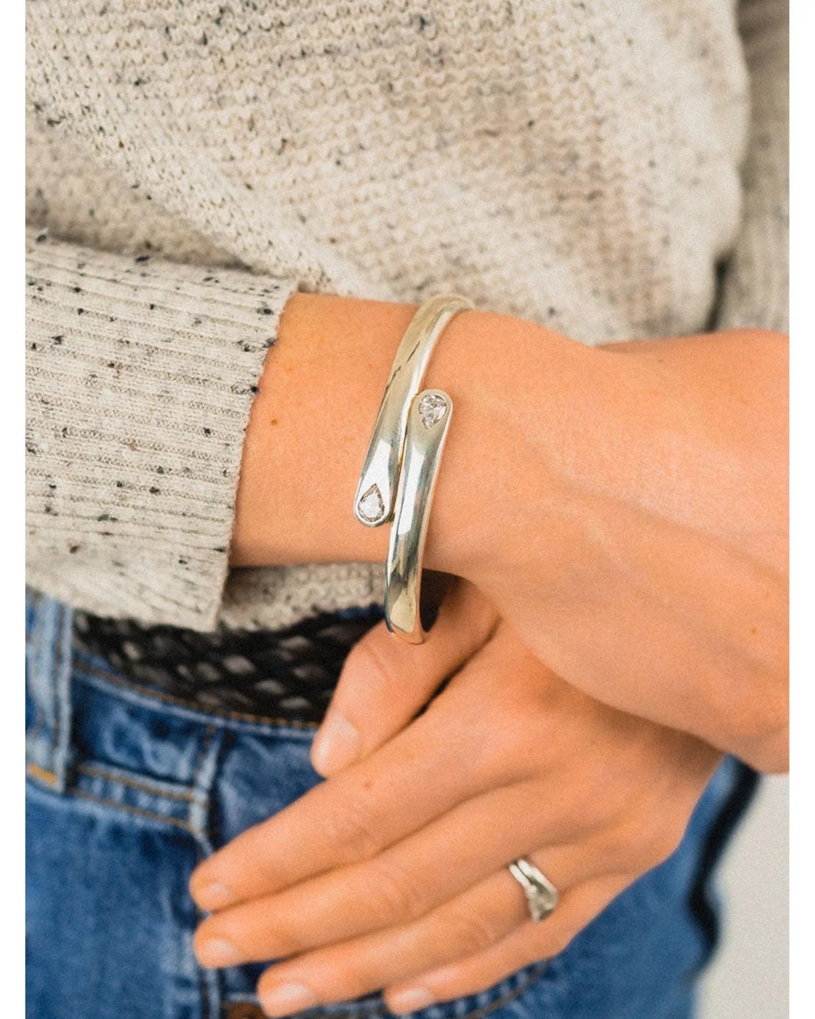 Sterling silver diamond cuff bangle with organic curves on a wrist, casual outfit