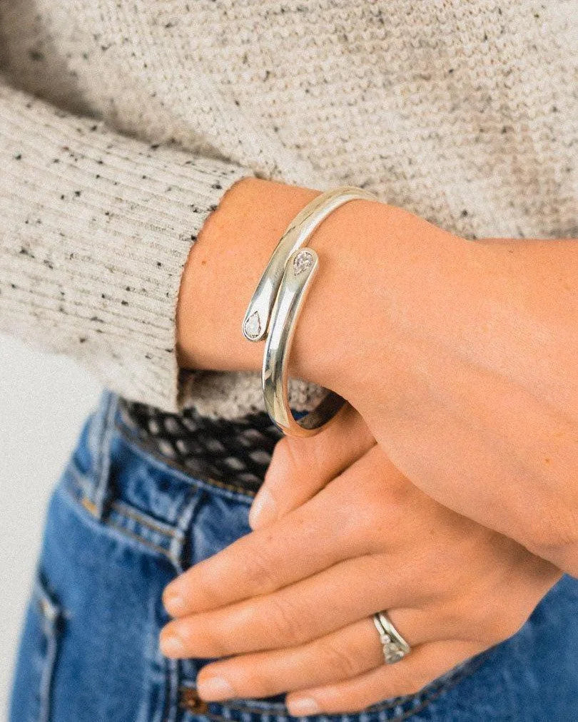 Silver diamond cuff bangle with organic teardrop ends on wrist, worn with casual outfit