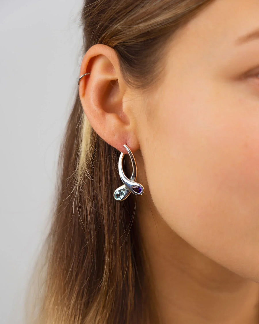 Sapphire and diamond drop earrings with organic curves worn on ear, handmade luxury jewellery