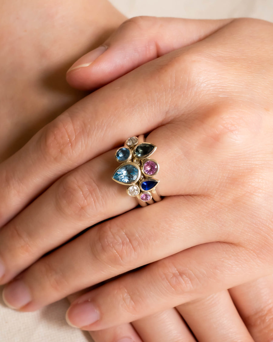 Gold stacking ring set with multi-coloured aquamarine and sapphire pear gemstones.