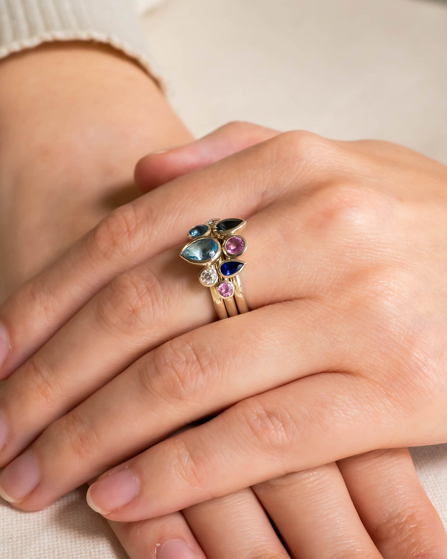 Gold stacking rings with multi-coloured aquamarine and sapphire pear gemstones.