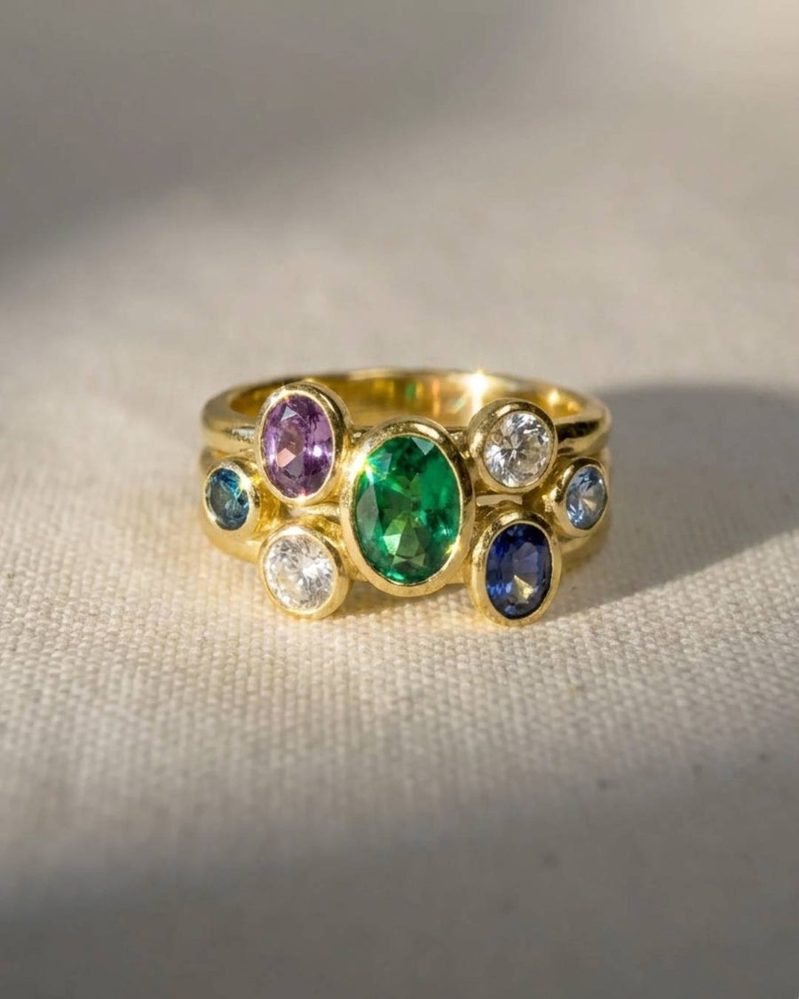 Gold ring with multi-coloured oval sapphires, emerald, and diamonds.