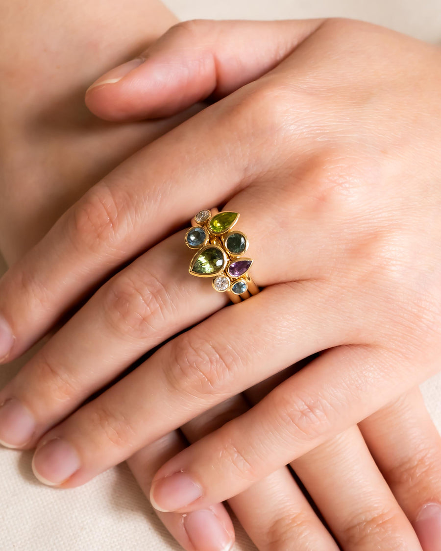 Gold ring with multi-coloured pear shaped sapphires and diamonds on a hand.