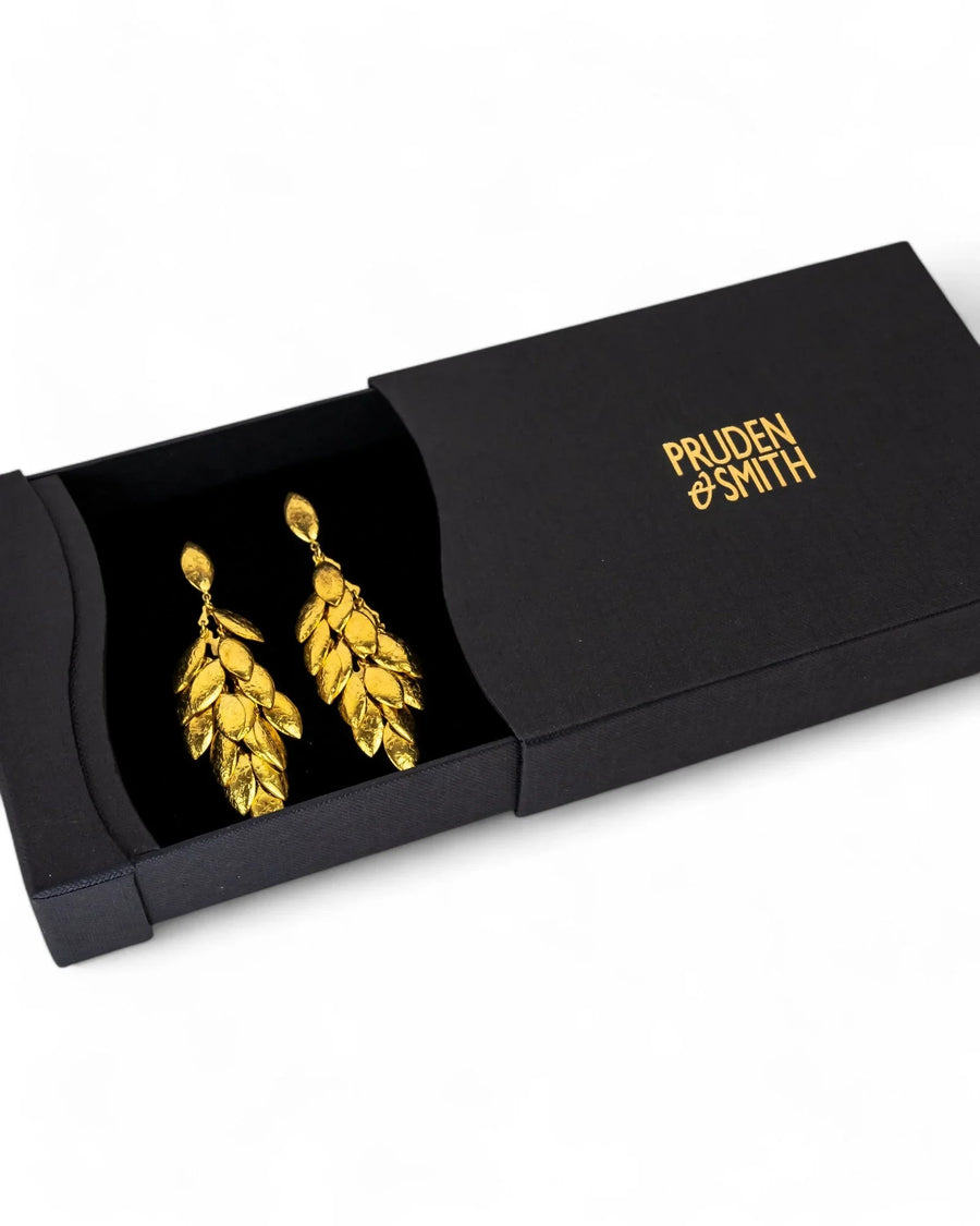 Gold multi-leaf long drop earrings in a black gift box.