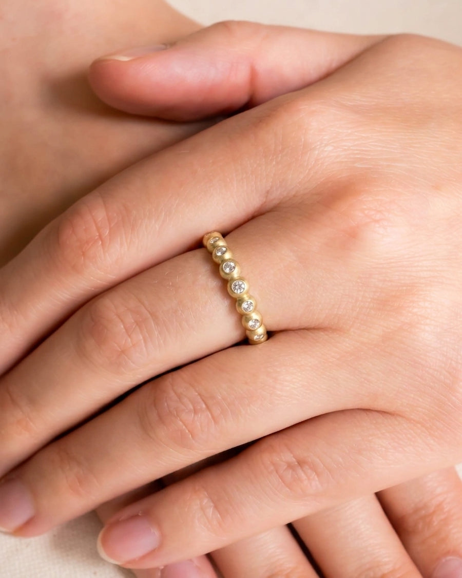 Yellow gold nugget eternity ring with dainty round diamonds.