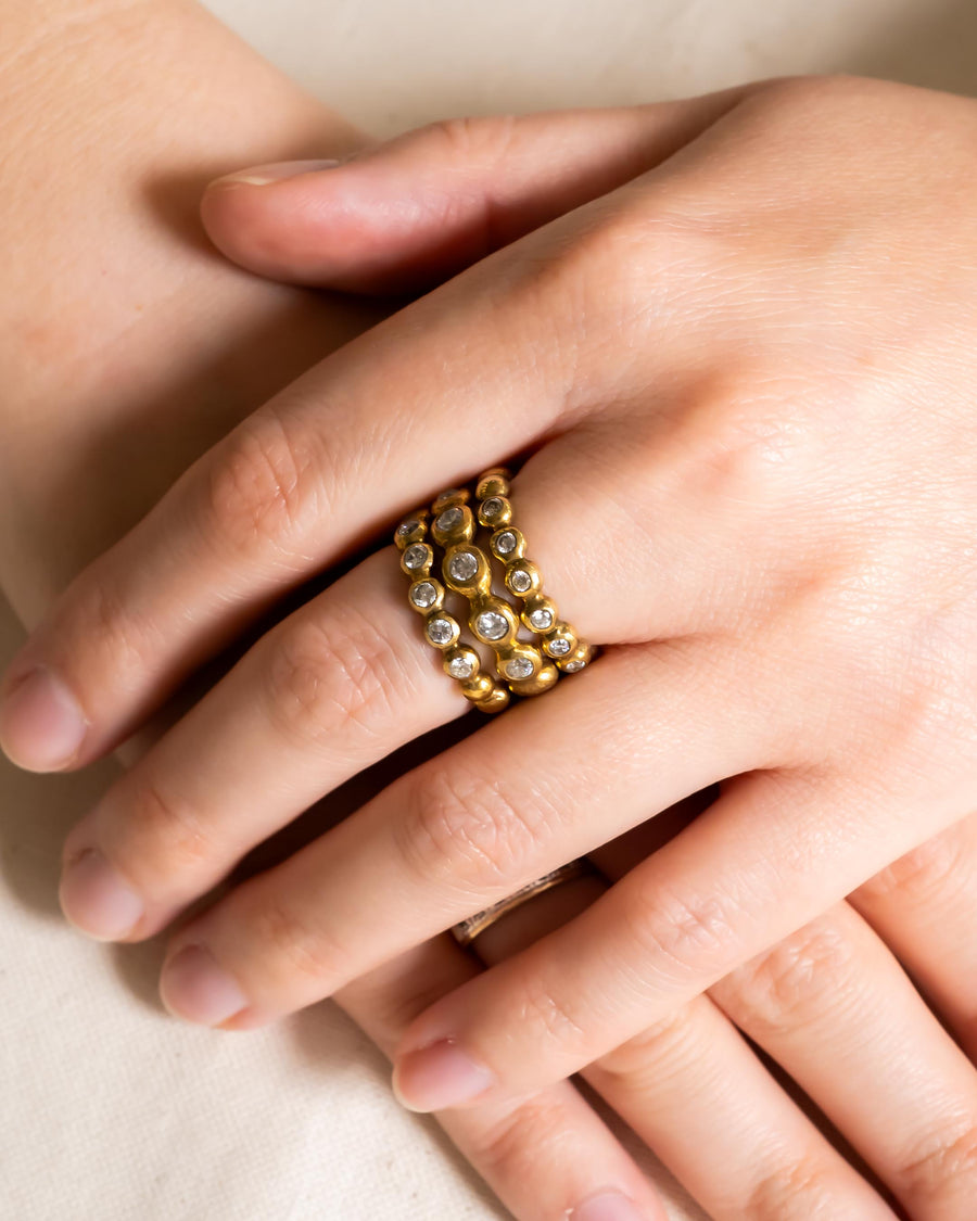 Gold nugget diamond stacking rings on a hand.