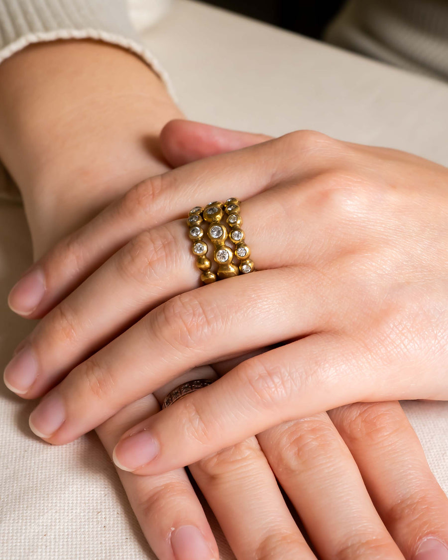 Gold stacking ring set with nugget diamonds on a hand.
