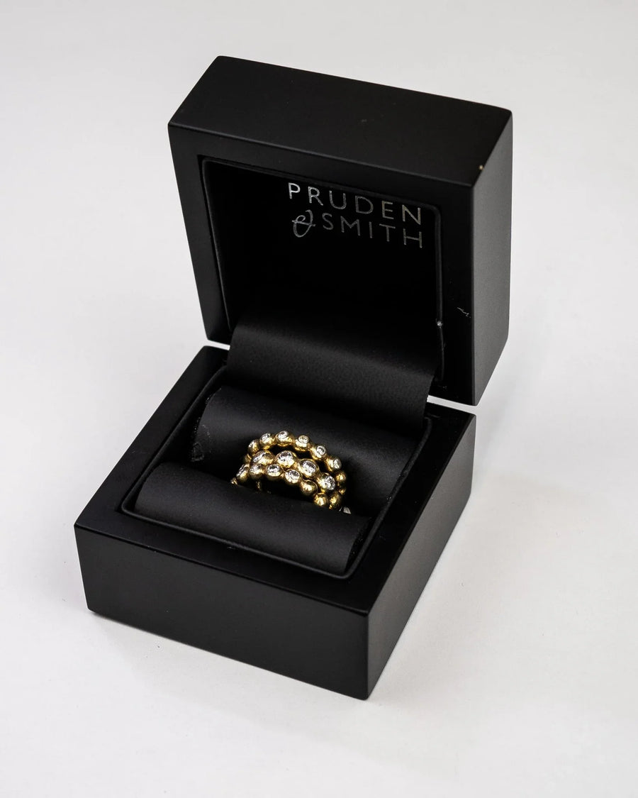 Gold stacking rings with nugget diamonds in a black box.