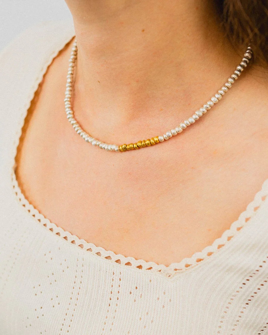 Handmade silver and gold beaded necklace with organic texture, worn on a woman's neck