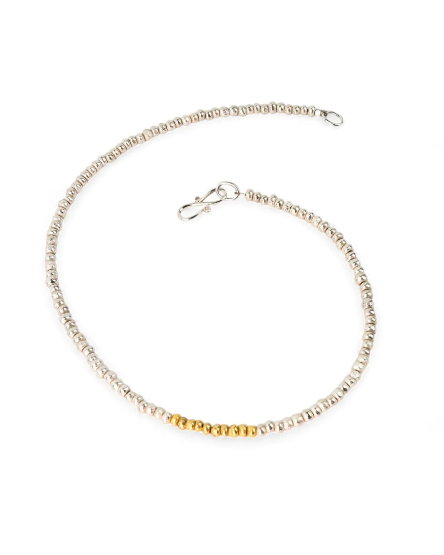 Handmade silver necklace with gold nugget beads and textured finish on white background