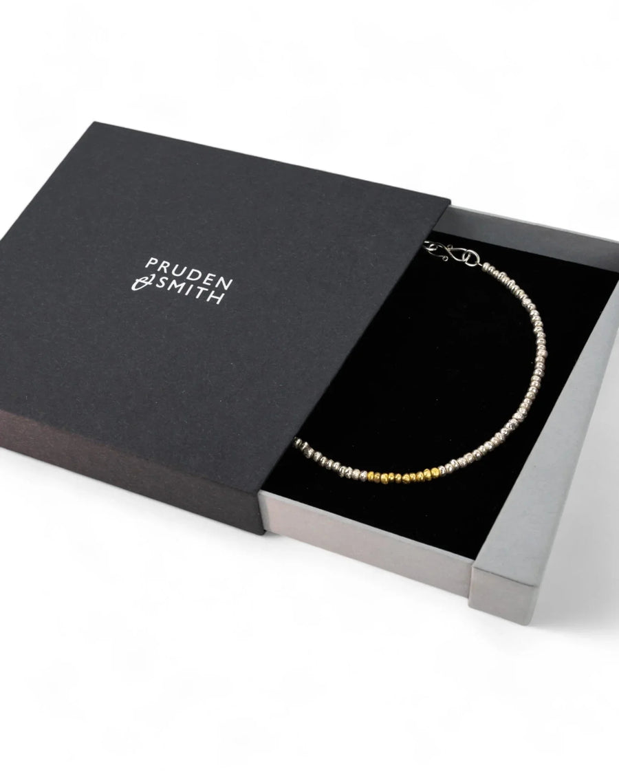 Gold and silver beaded nugget necklace displayed in a black presentation box