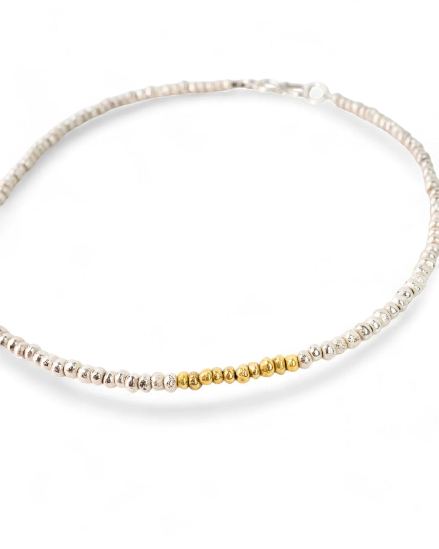 Handmade beaded silver necklace with central gold nugget detail on white background