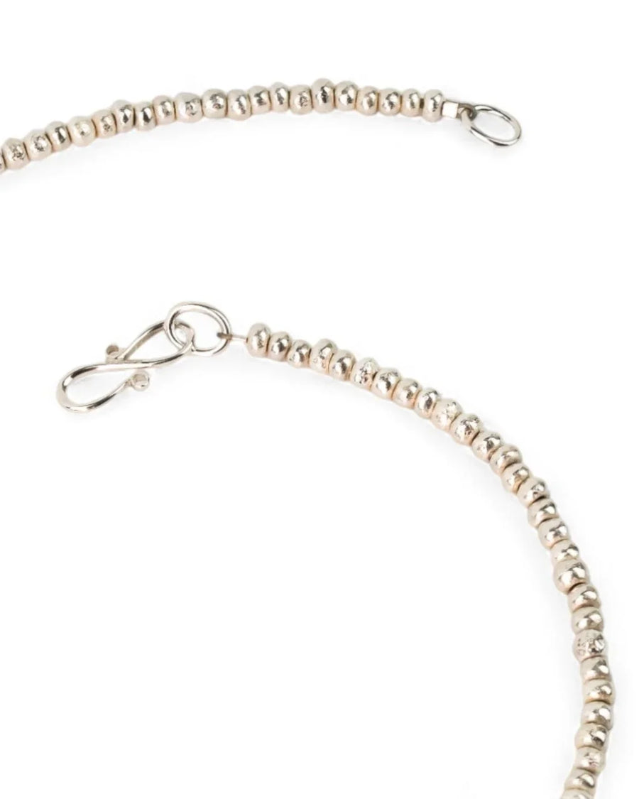 Close-up of a handmade silver beaded necklace with textured round beads and hook clasp