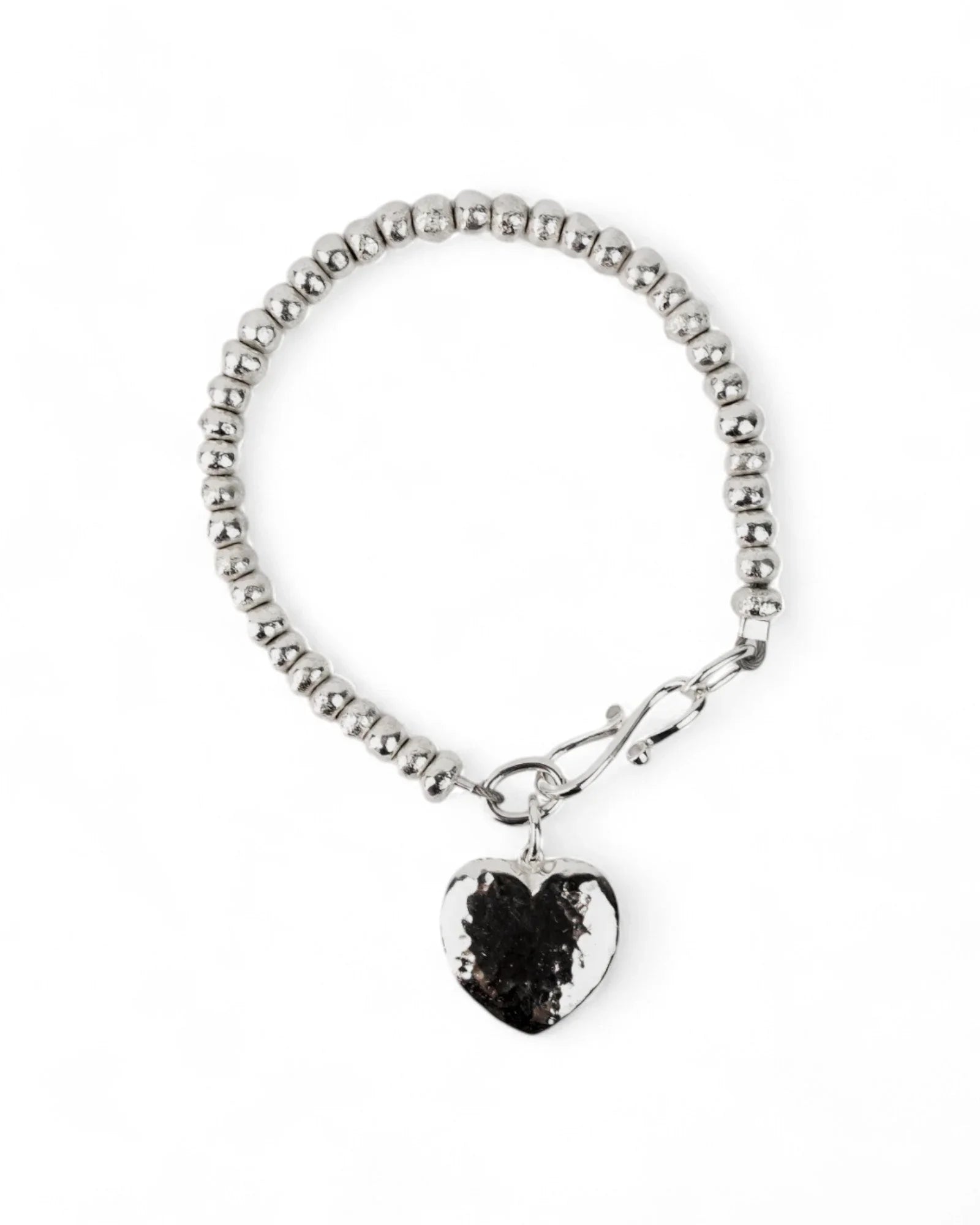 Silver beaded bracelet with a hammered heart charm and toggle clasp on white background