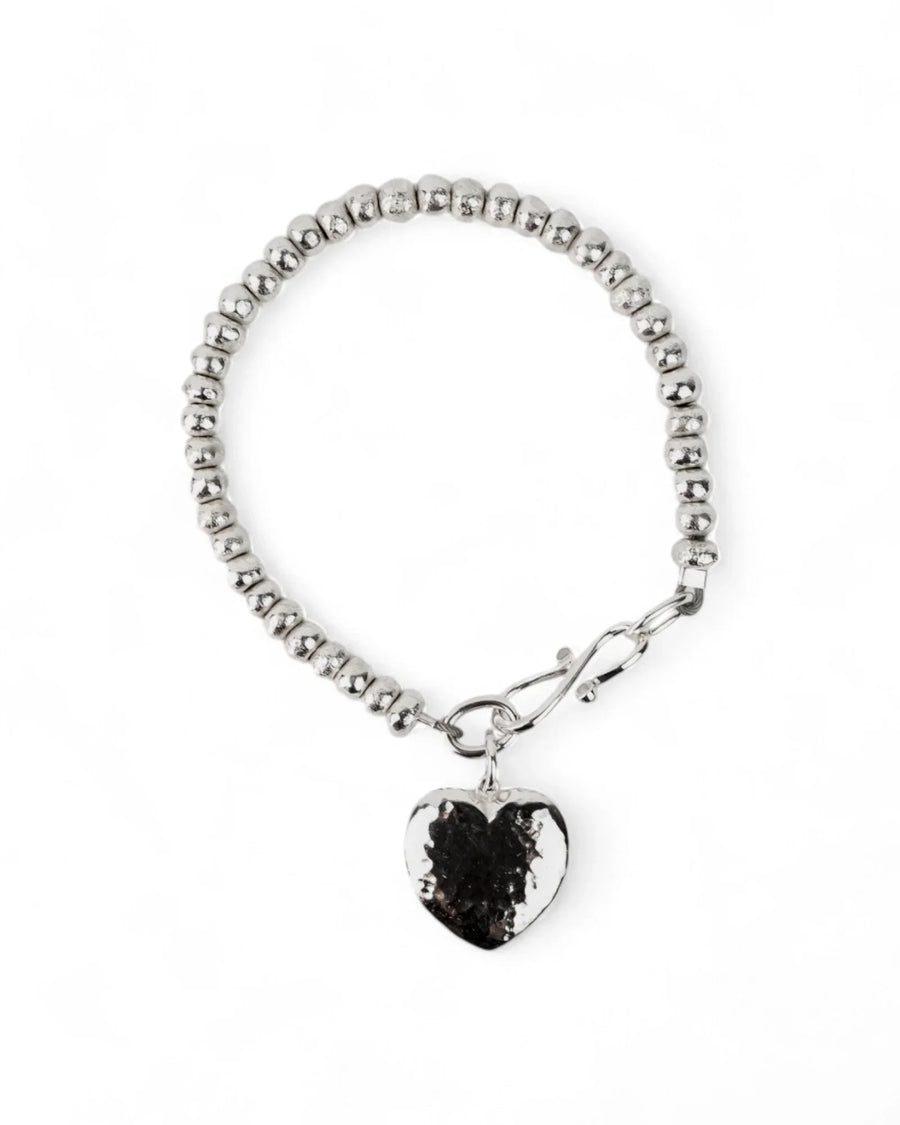 Silver beaded bracelet with a hammered heart charm and toggle clasp on white background