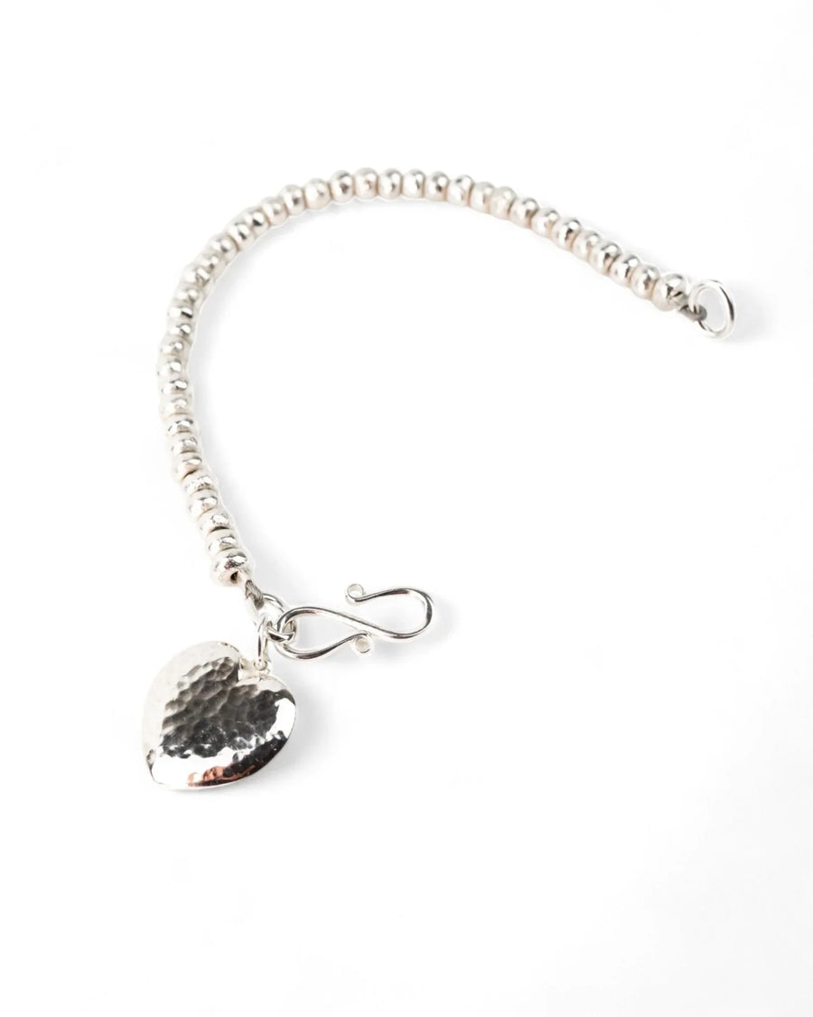 Hammered silver heart charm bracelet with nugget beads on a white background
