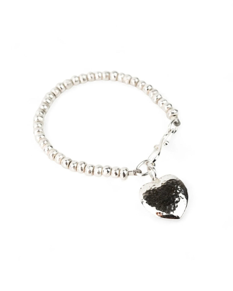 Hammered silver heart charm bracelet with beaded silver band on white background