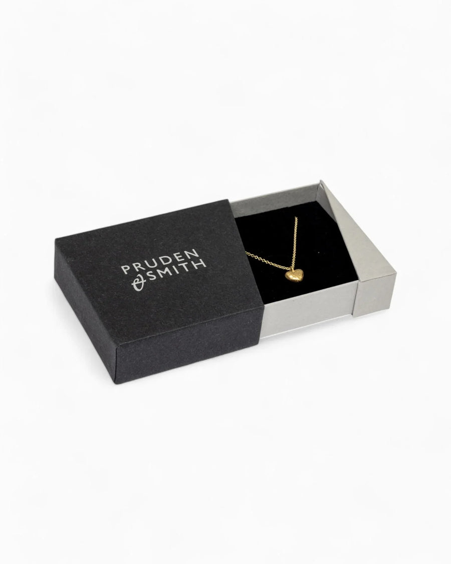 Gold nugget heart pendant on a chain in an open black gift box.
