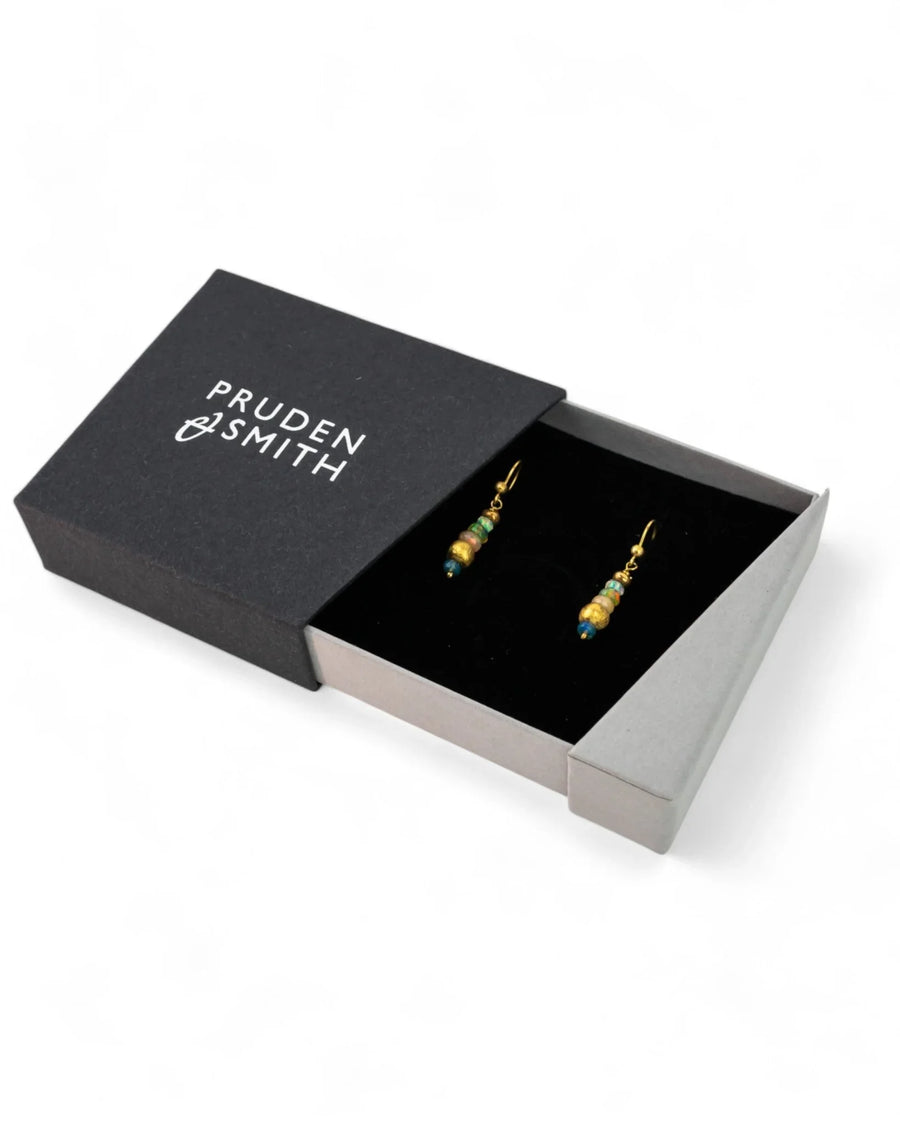 Dangly gold earrings with opal nuggets displayed in a black gift box