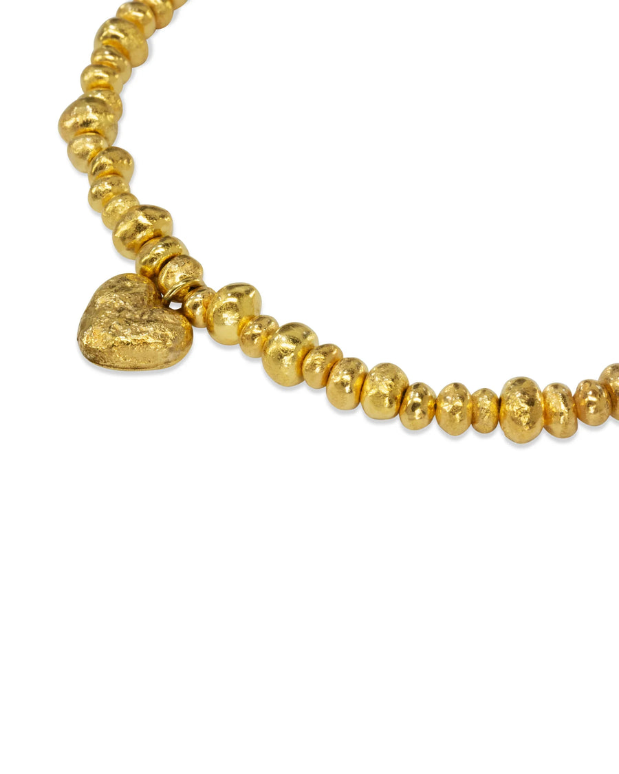 Handmade gold nugget bracelet with a textured heart charm on white background