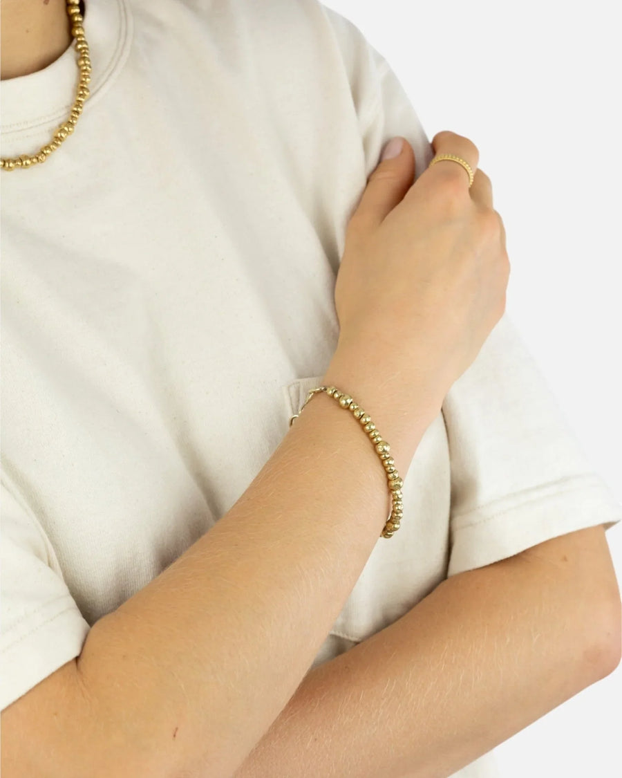 Woman wearing an organic 9ct gold nugget bracelet with matching ring and necklace