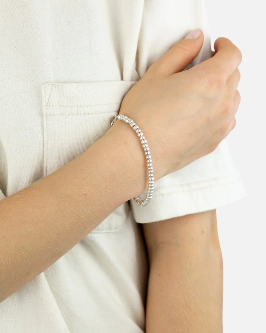 Solid silver beaded bracelet with organic texture on wrist, worn with casual cream top