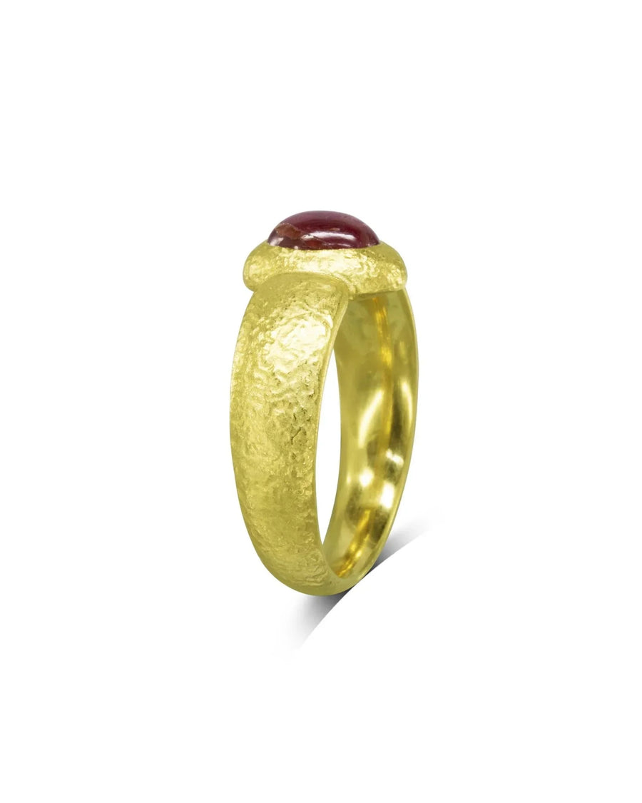 Yellow gold ring with a textured band and a cabochon ruby gemstone.