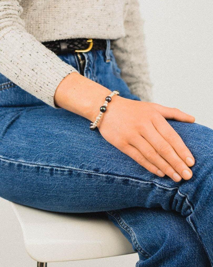 Woman wearing a silver and black pearl bracelet with organic nugget beads