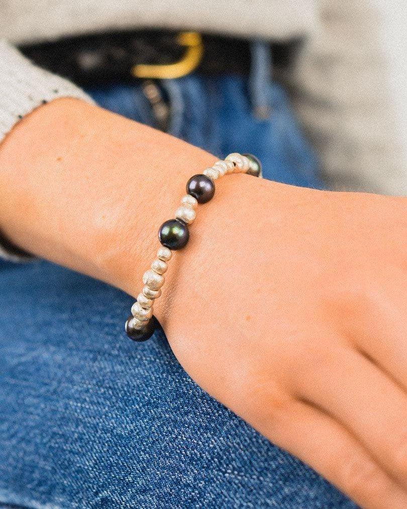Silver and black pearl beaded bracelet worn on wrist, modern casual outfit style