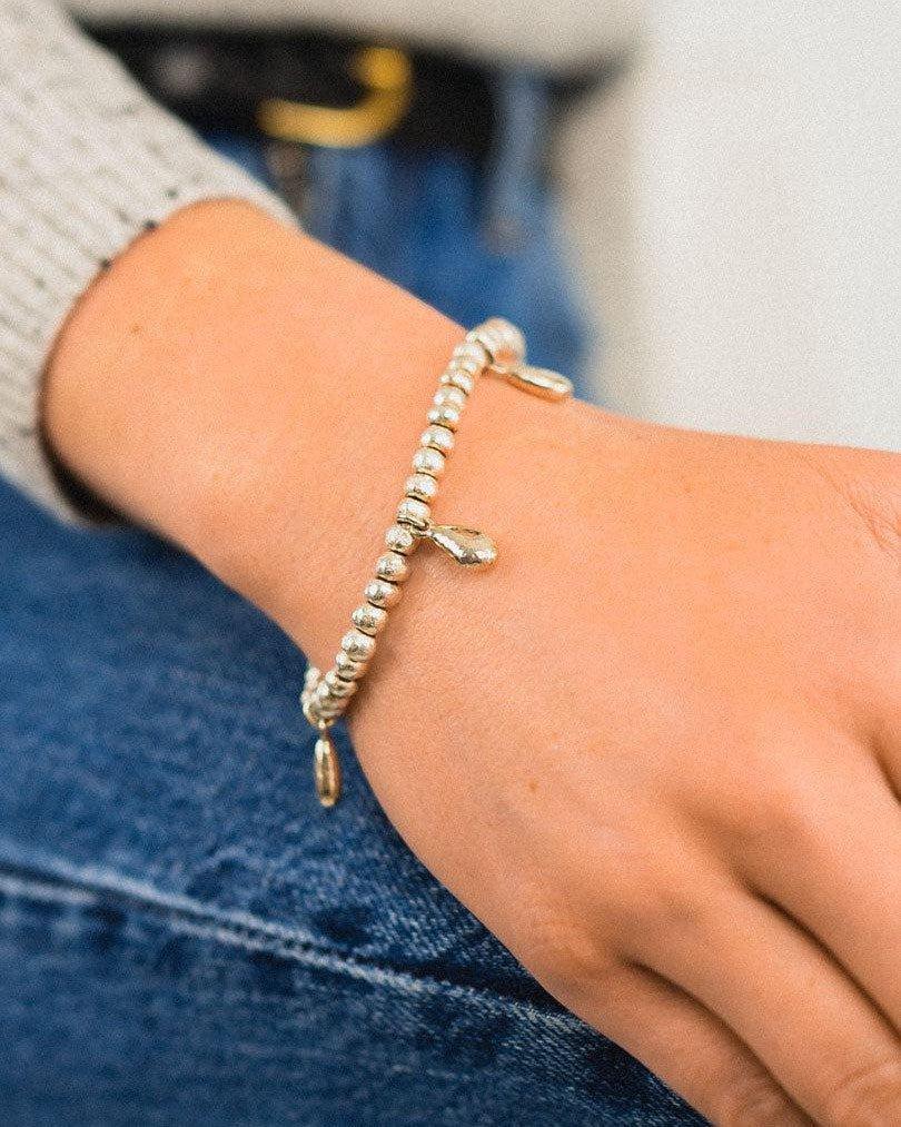 Silver beaded bracelet with teardrop charms on wrist, casual handcrafted jewellery
