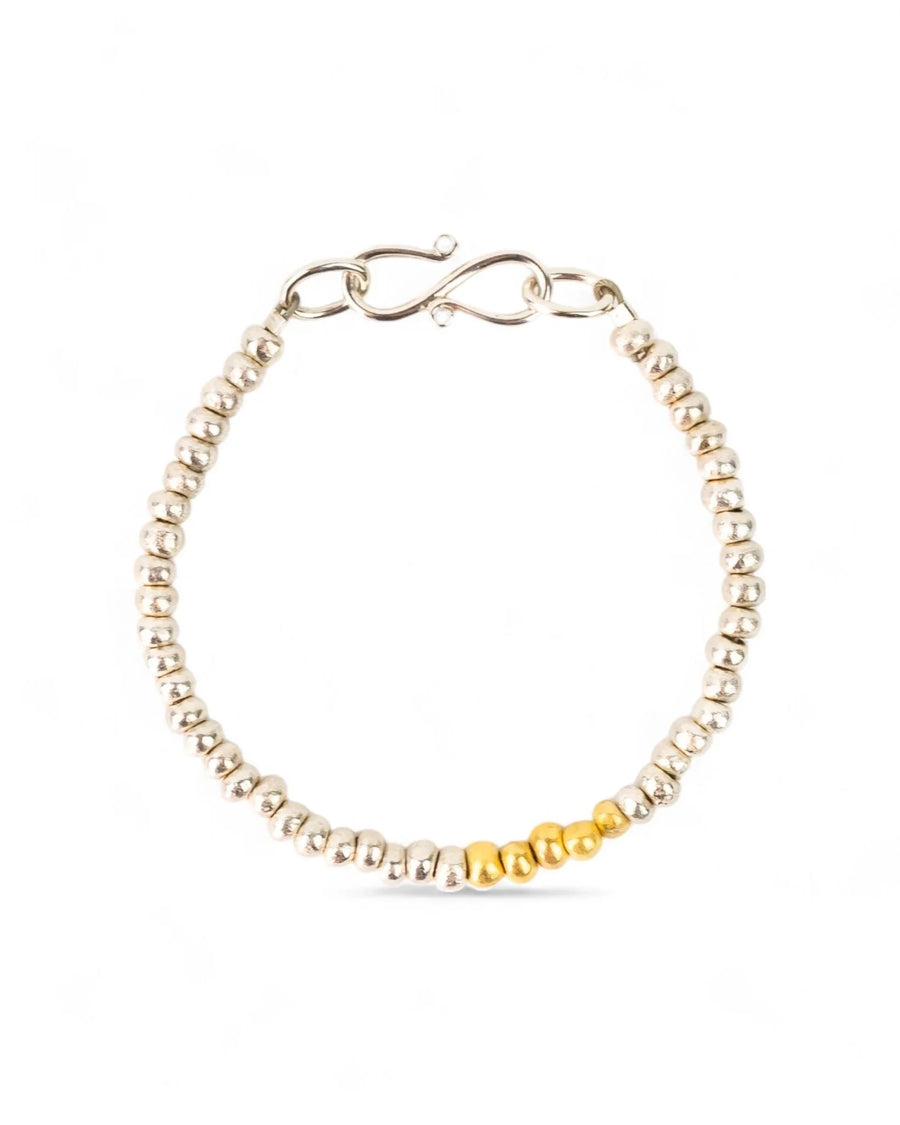 Beaded silver bracelet with gold accent section and handmade clasp on white background