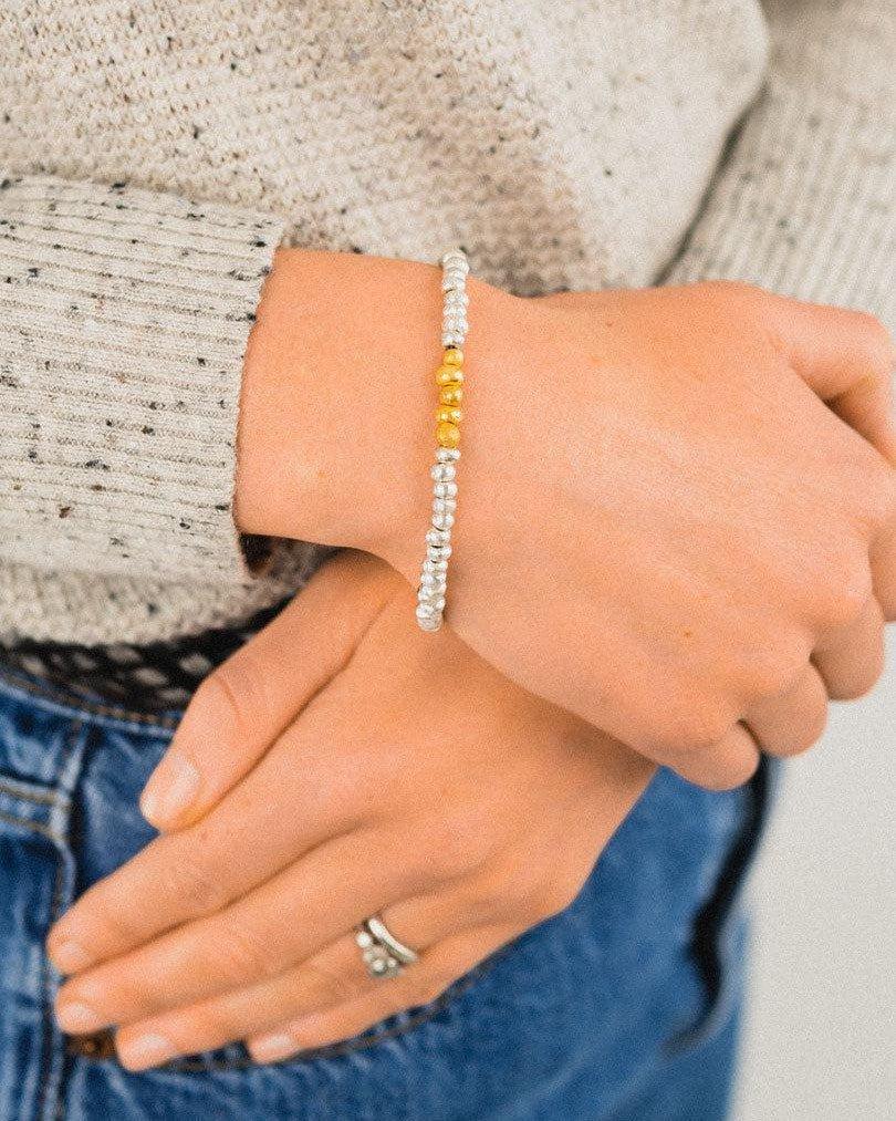 Handmade silver nugget bracelet with gold bead section on wrist, casual outfit
