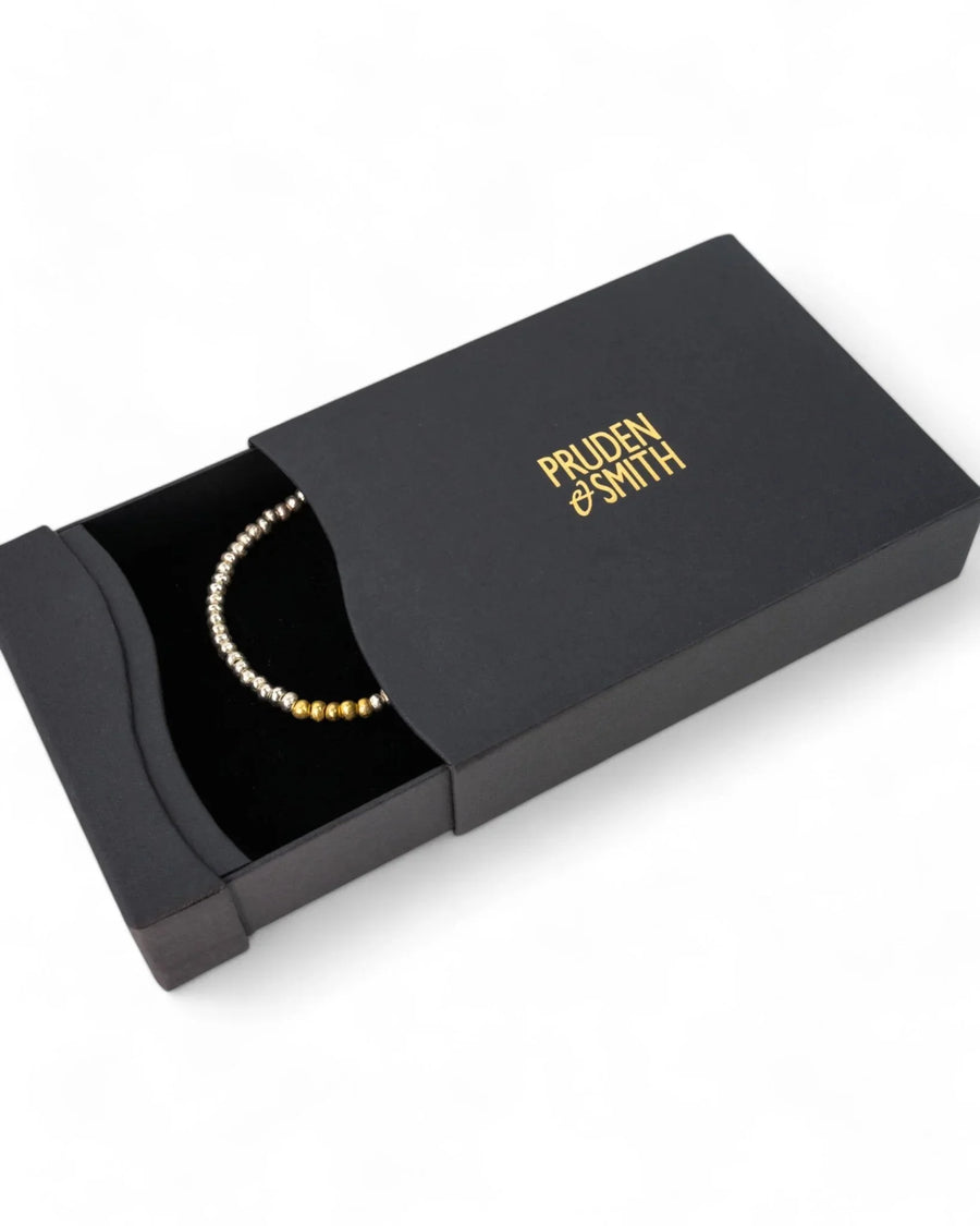 Elegant silver and gold beaded bracelet in a sleek black gift box on a white background