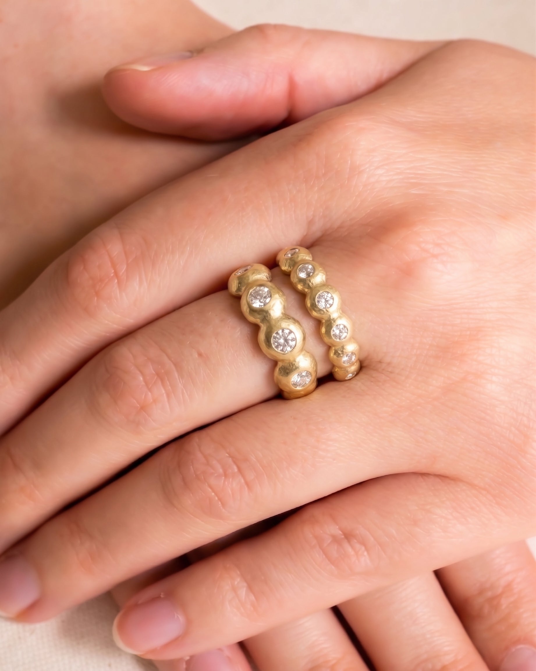 Nugget yellow gold diamond eternity rings with bubble design on a hand.