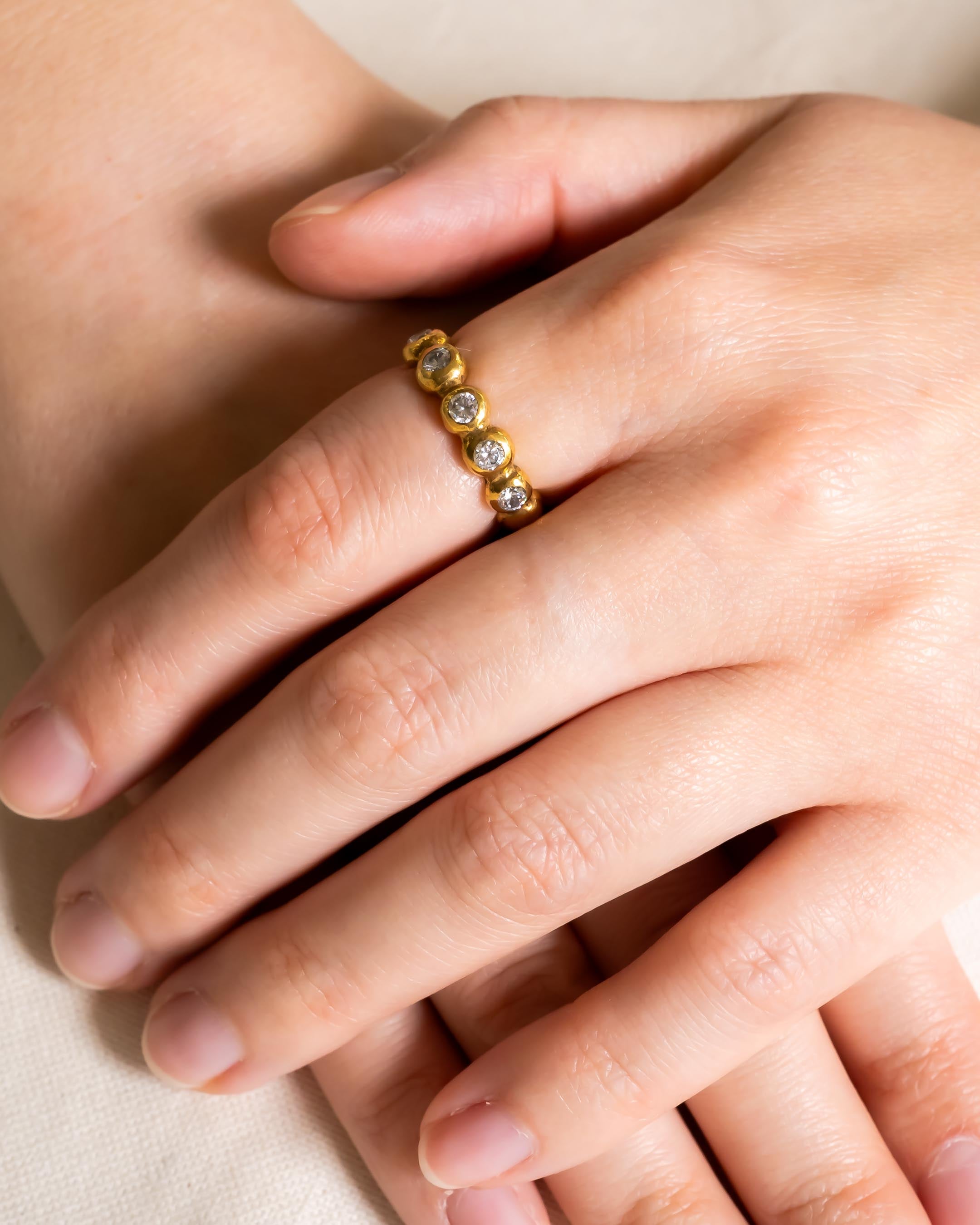 Nugget yellow gold diamond full eternity ring on a hand.